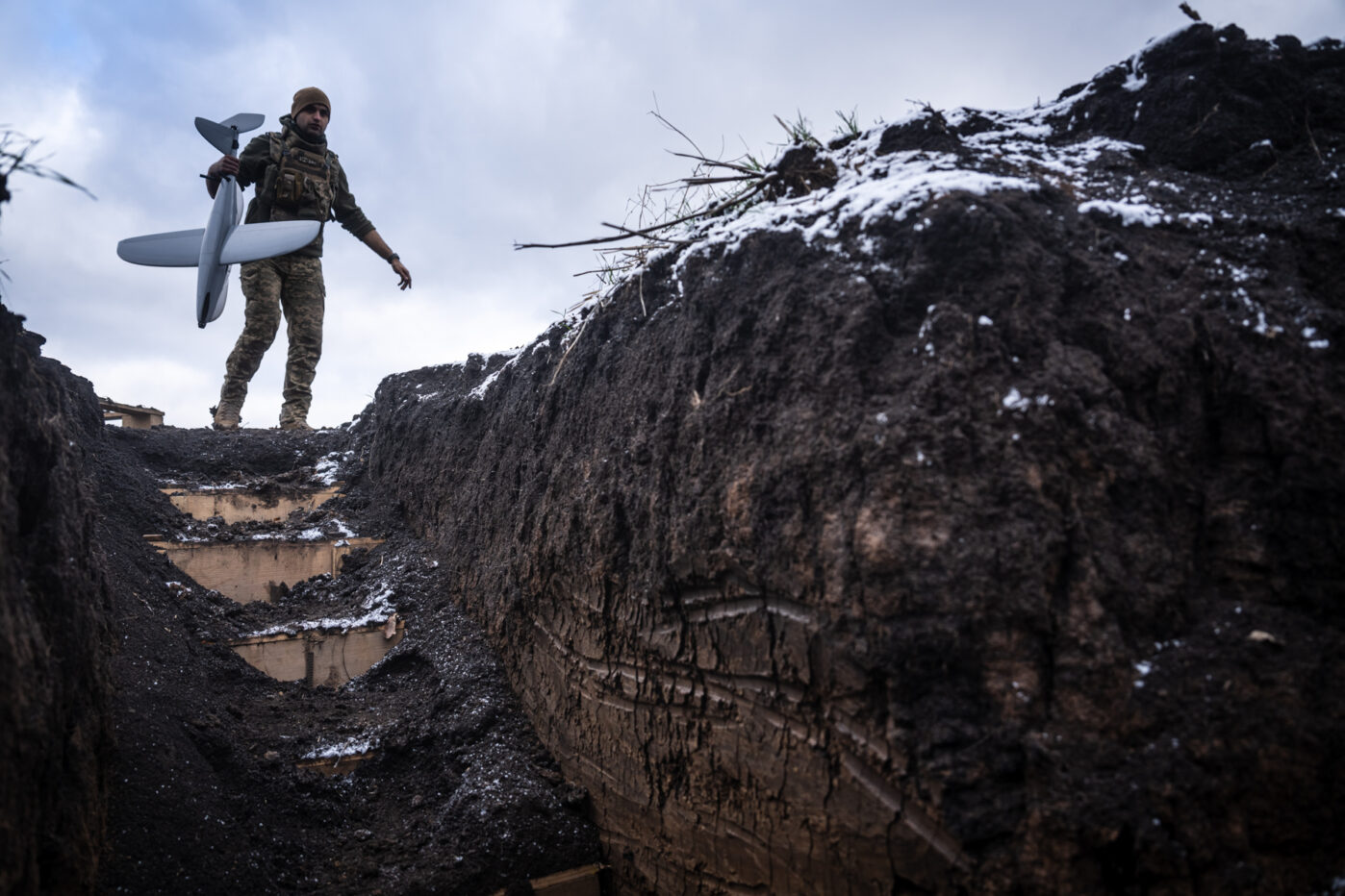 Украинский военнослужащий несет разведывательный беспилотник во время перемещения по окопам в районе Покровска